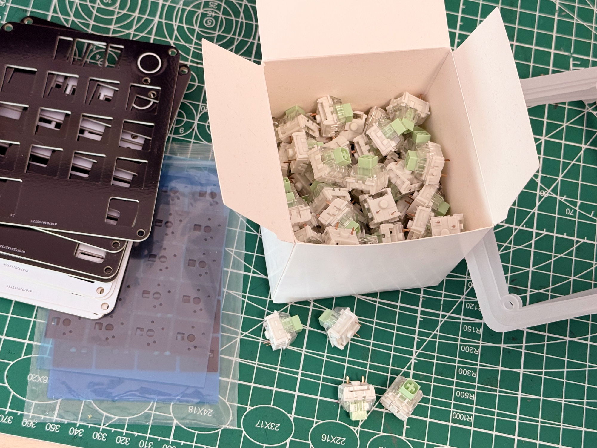 A box of Kailh Box Jade switches beside AgentPad13 plates and case parts.